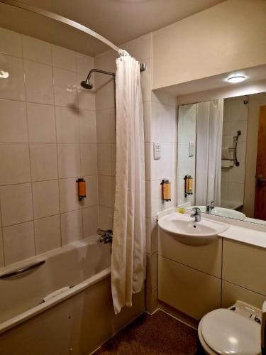 a bathroom with a sink and a tub and a toilet at Charter Hotel Bournemouth in Bournemouth