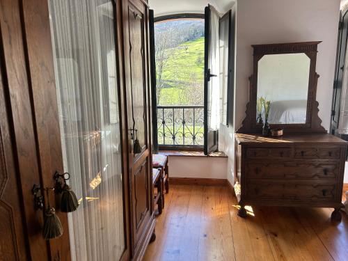a room with a mirror and a dresser and a window at Casa Caiceda in Poo de Cabrales