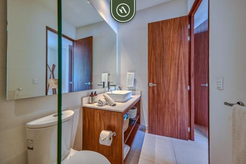 a bathroom with a toilet and a sink and a mirror at 2BR Condo with Rooftop Pool - 2 Min Walk to Beach in Bucerías