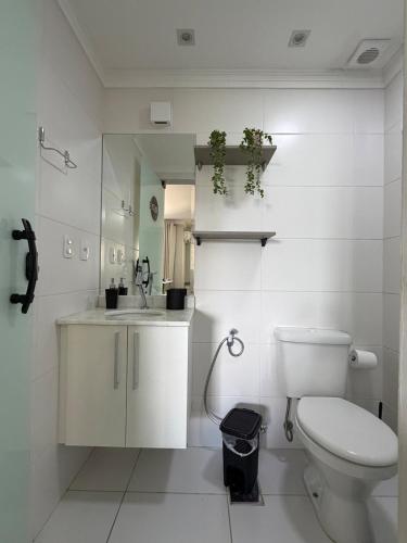 a white bathroom with a toilet and a sink at Flat Red Encanto in Sorocaba