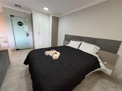 a bedroom with a bed with two stuffed animals on it at Flat Red Encanto in Sorocaba