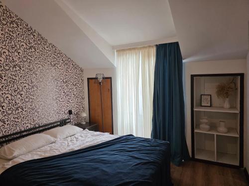 a bedroom with a bed and a window with blue curtains at Urban House in Batumi