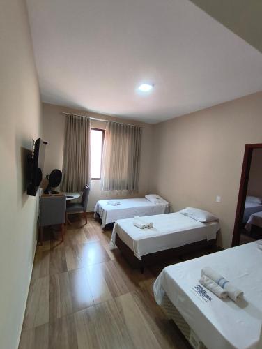 a hotel room with two beds and a television at Hotel Colibri Viçosa - Próximo a UFV in Viçosa