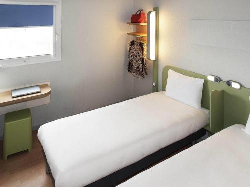 a small room with two beds and a window at ibis budget Goussainville Charles de Gaulle in Goussainville