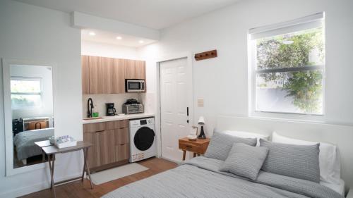 a white bedroom with a bed and a kitchen at Stylish Studio Near Wynwood & Design District in Miami