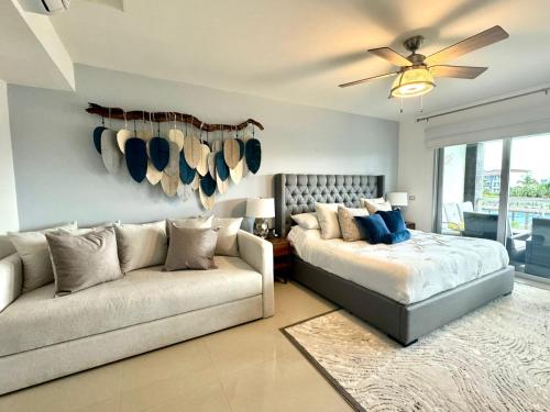 a bedroom with a bed and a couch and a fan at Condo/ Depa - Marea Azul - Playa del Carmen in Playa del Carmen