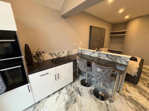 a kitchen with a marble counter top and two chairs at The Norwich Hideaway - Private Hot Tub in Norwich