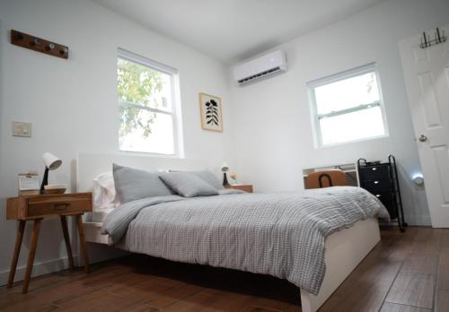 a white bedroom with a bed and two windows at Stylish Studio Near Wynwood & Design District in Miami