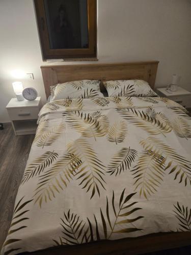 a bed with a black and white comforter with a cat on it at Kuća za odmor Velnira in Ozalj