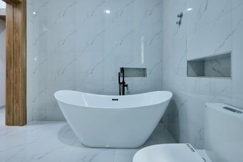 a white bathroom with a tub and a toilet at Buddy's Court Luxury 5Bedroom,3 & 2bed Apartment in Ikeja