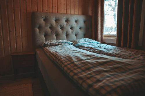 ein Bett mit einer karierten Decke und einem Fenster in der Unterkunft Solyun in Hol