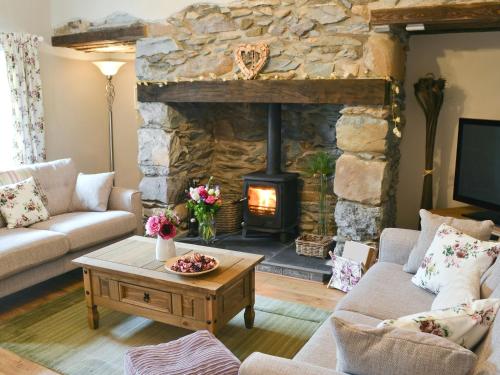 a living room with a stone fireplace and a table at Llifon in Llanwnda