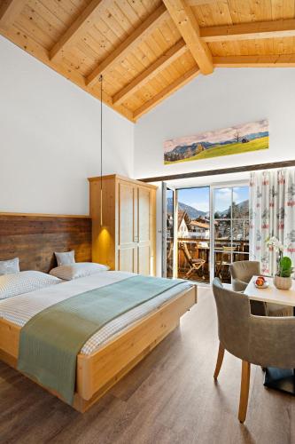 a bedroom with a large bed and a table and chairs at Hotel Bergsonne Allgäu in Sonthofen