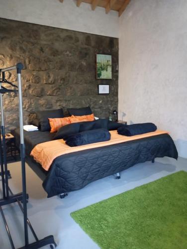a bedroom with two beds and a stone wall at Basaltic House Pedreira in Lomba da Pedreira