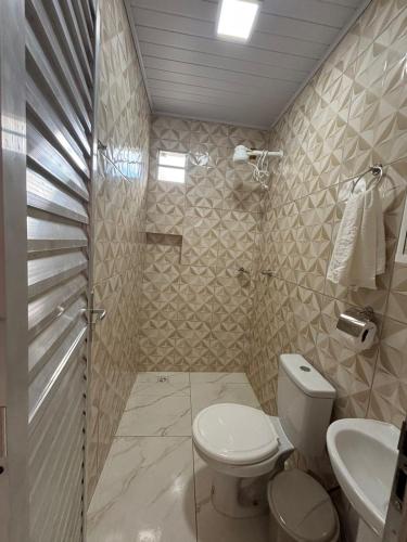 a bathroom with a toilet and a sink and a shower at Pousada Bela Rosa in Santa Cruz Cabrália
