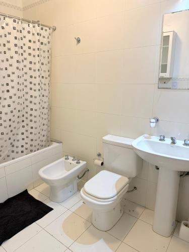 a white bathroom with a toilet and a sink at Cabildo Apart Familiar in Santiago del Estero