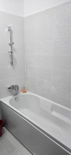eine weiße Badewanne in einem weiß gefliesten Badezimmer in der Unterkunft Studio Ajustorului rezidence ,Lacu Morii in Bukarest