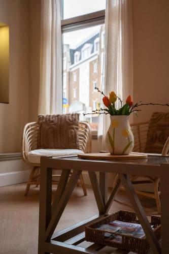 a living room with a table and a vase with flowers at Tussen poort en toren in Sneek