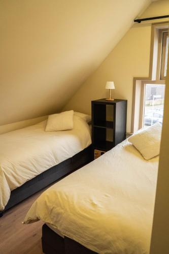 two beds in a attic bedroom with a window at Tussen poort en toren in Sneek
