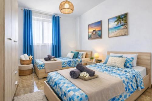 a bedroom with two beds with blue and white sheets at Bright & Spacious 3 Bedroom Apartment close to Marsaskala seafront in Marsaskala