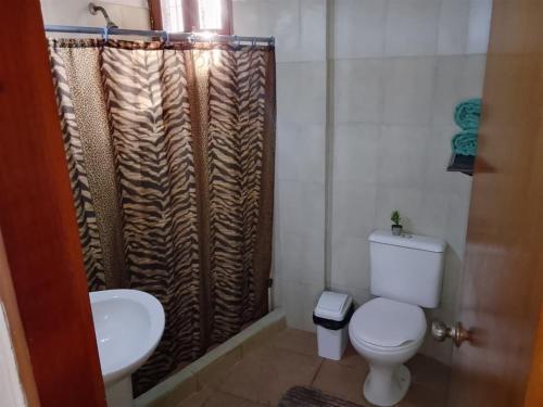 a bathroom with a toilet and a shower curtain at El Refugio II, cerca Playa El Agua y Playa Parguito, VENEZUELA in Loma de Guerra