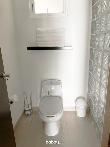 a bathroom with a toilet with a window and towels at Departamento Isla Marina Mazatlán con alberca in Mazatlán