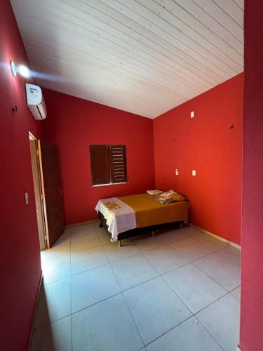 a bedroom with a bed in a red wall at Pousada Raios do Sol in Amontada