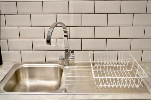 a sink with a faucet and a dish drying rack at Spacious 4BR Apartment 7 Beds Near Station in Newport