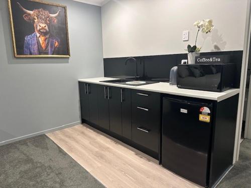 a kitchen with black cabinets and a painting of a cow at Thornton Hideaway in Cambridge