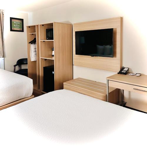a bedroom with a bed and a desk and a television at Baymont by Wyndham Missoula in Missoula