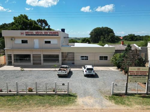 two cars parked in a parking lot in front of a building at Hotel e Restaurante Rota do Pampa in Estância Teixeira