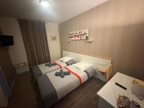 a hotel room with two beds and a desk at Hôtel du Centre in Gueugnon