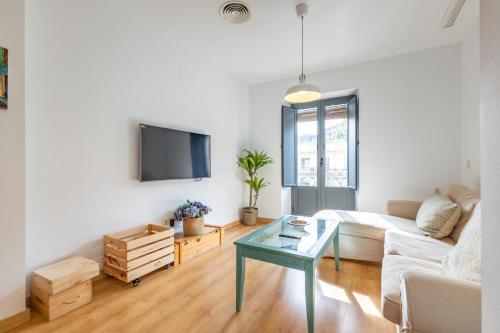 a living room with a white couch and a table at Alma de San Bernardo in Seville