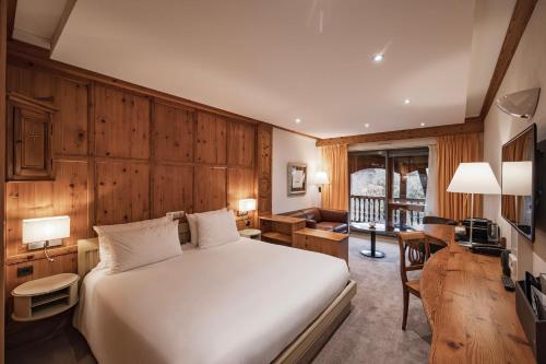 a bedroom with a white bed and a living room at YONA ex Le Parc Hôtel in Obernai