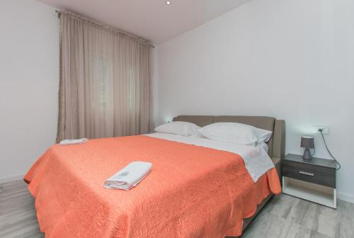 a bedroom with a bed with an orange blanket at Apartment Adriatic panorama view in Omiš