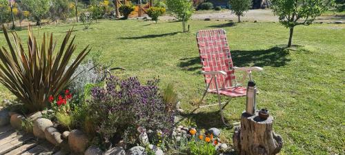 a red chair sitting in a garden with flowers at Cabañas SurEnya in El Bolsón