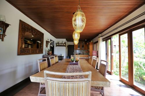 a dining room with a long wooden table and chairs at The Sanyas Retreat in Tabanan