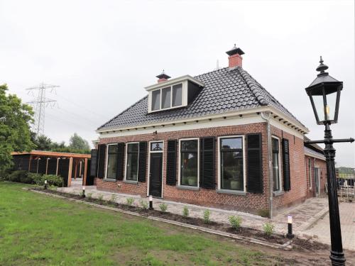 a red brick house with a roof at Stylish Farmhouse with Spa Tub in Kootstertille