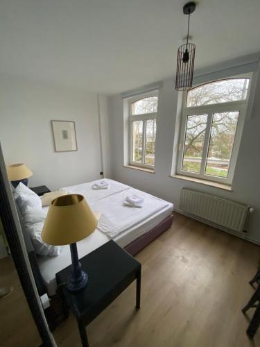 a bedroom with a bed and a lamp and two windows at Tanne Grand Palace in Alleringersleben