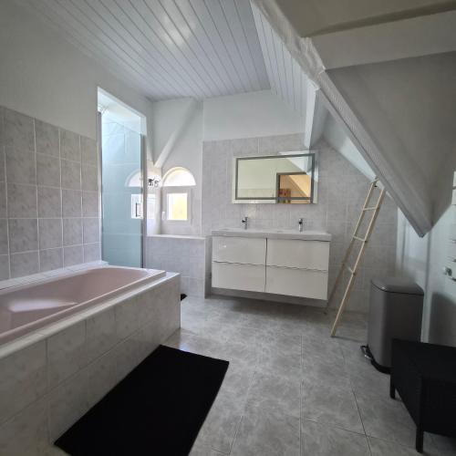 a bathroom with a tub and a sink and a mirror at "La Villa du Cap" avec piscine intérieur, billard et à 5 minutes de la plage et des commerces! in Fouesnant