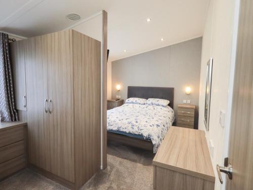 a bedroom with a bed and a wooden cabinet at Lily's Lodge in Morecambe
