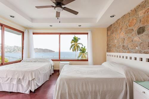 two beds in a room with a large window at Private villa, 6 bedrooms, 2 pools with views in Acapulco