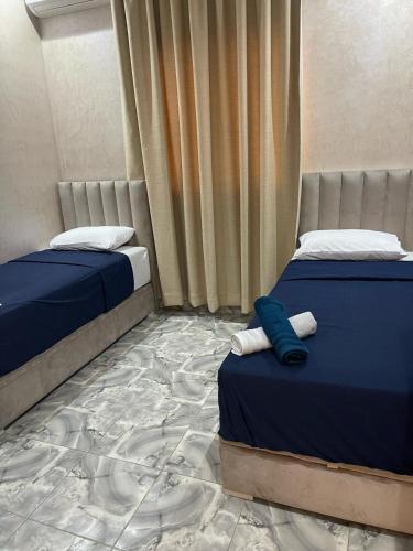 a bedroom with two beds with blue sheets and a carpet at villa lina in Aït Mazou