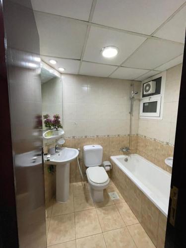a bathroom with a toilet and a sink and a tub at Panoramic Sea apartment & Skyline View Private Room in Sharjah
