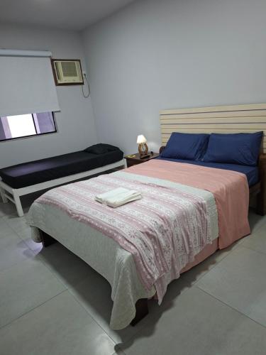 a bedroom with a large bed and a chair at Apartamento Brisa do Mar - Casas confortáveis para casal e acompanhantes com garagem in Búzios