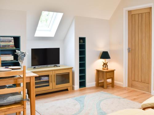 a living room with a tv on a stand with a desk at Leveret Lodge in Burgh