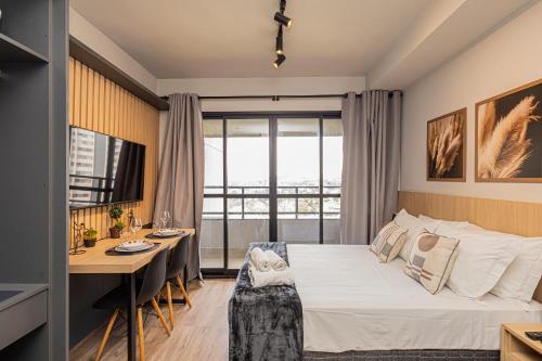 a bedroom with a bed and a table and a desk at Sky Design Residence in Barueri