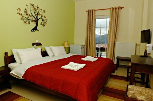 a bedroom with a red bed with two towels on it at Ksenonas Biktoria in Loutra Amarantou