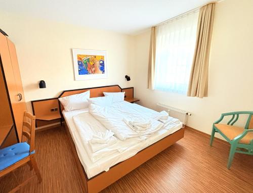 a bedroom with a bed and a chair and a window at Boddenhof Apartment 48 - Terrasse für Hundefreunde in Buschvitz