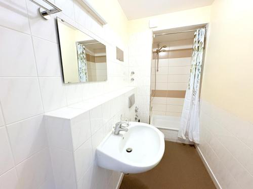 a white bathroom with a sink and a mirror at Boddenhof Apartment 52 - Balkon, hundefreundlich in Buschvitz